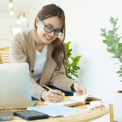 woman writing notes while sitting at a laptop